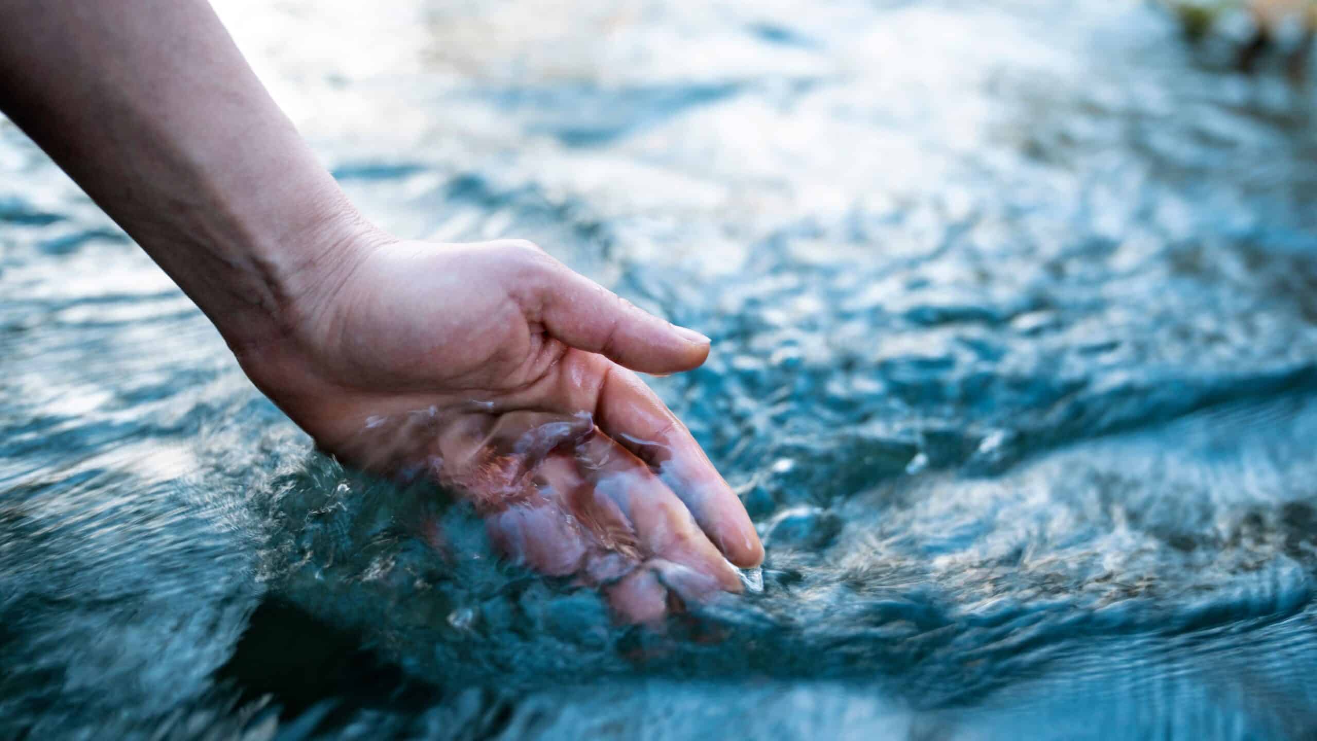 Eine Frau hält ihre Hand in einen Fluss