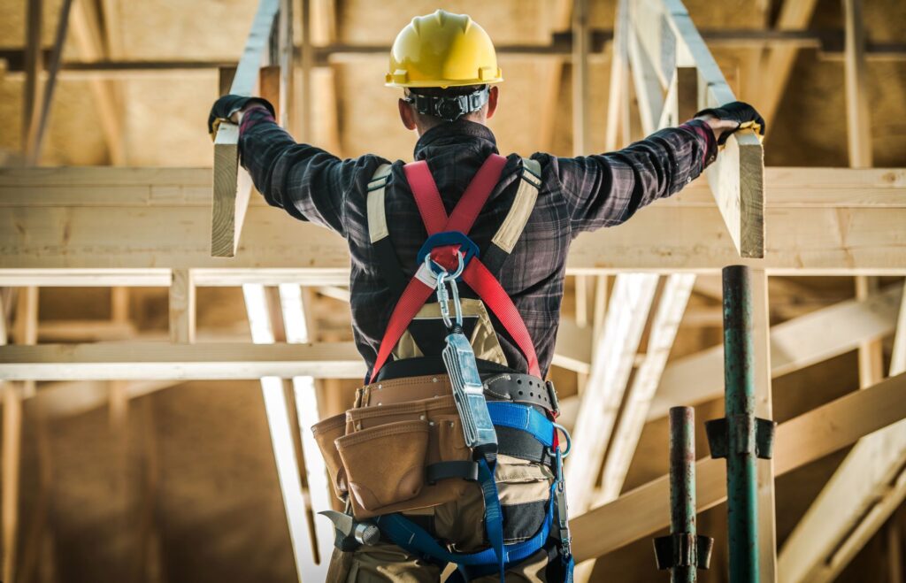 Arbeiter mit Sicherheitsgurt auf Baustelle bei Höhenarbeiten.