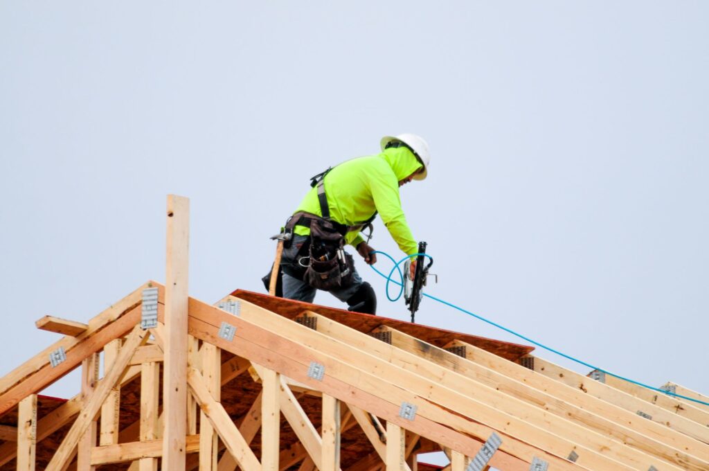 Bauarbeiter bei Arbeiten auf einem Holzdach mit Werkzeug.